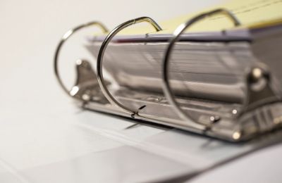 An open ring binder of documents on a desk.