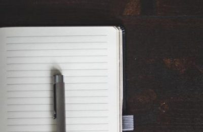 An open lined notebook with a pencil resting on the page.